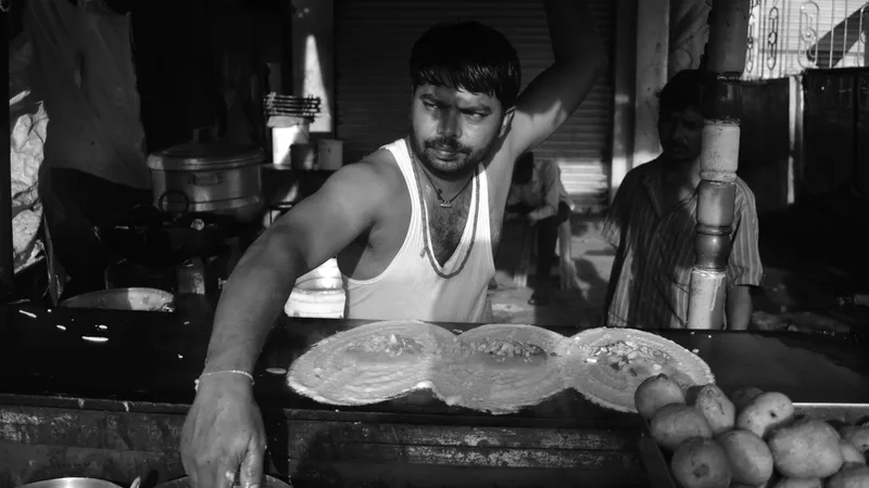 Chef cooking fresh dosas on a flat-top grill at an outdoor catering event